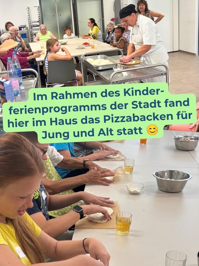 Das Bild zeigt Bewohner und Kinder beim Backen von Pizza