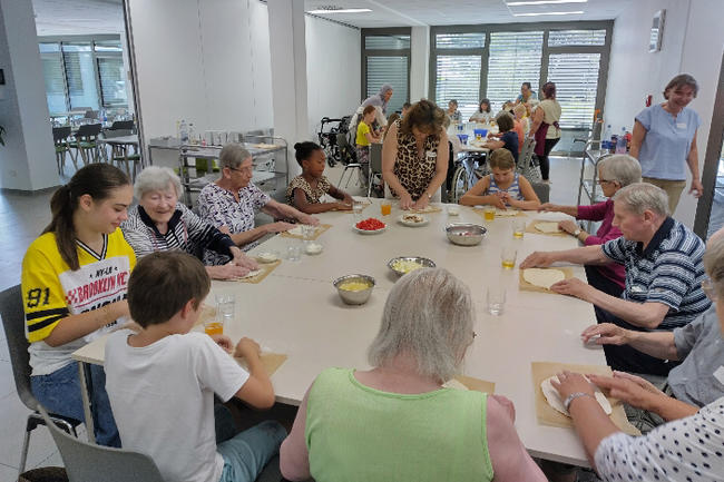 Das Bild zeigt unsere Bewohner und Kinder beim Pizza backen